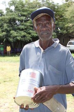 A food aid beneficiary after receiving a can of vegetable oil አንድ ተረጂ የምግብ ዘይት እርዳታ ተቀብለው