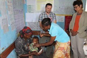 Ambassador Haslach observing a malnourished child being examined by a health extension worker at the health post አምባሳደር ሃስላክ በጤና ኬላው የጤና ኤክስተንሽን ባልደረባዋ በምግብ እጥረት ለተጎዳ ህጻን ምርመራ ስታደርግ ተገኝተው በተመለከቱበት ወቅት 