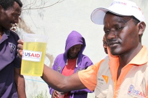 World Vision staffer distributing vegetable oil to food aid recipients at Abela Faricho JOEP Food Distribution Point, Humbo district በአቤላ ፋርቾ ወረዳ የወርልድ ቪዥን ባልደረባ ለእርዳታ ተቀባዮች የምግብ ዘይት ሲያድል